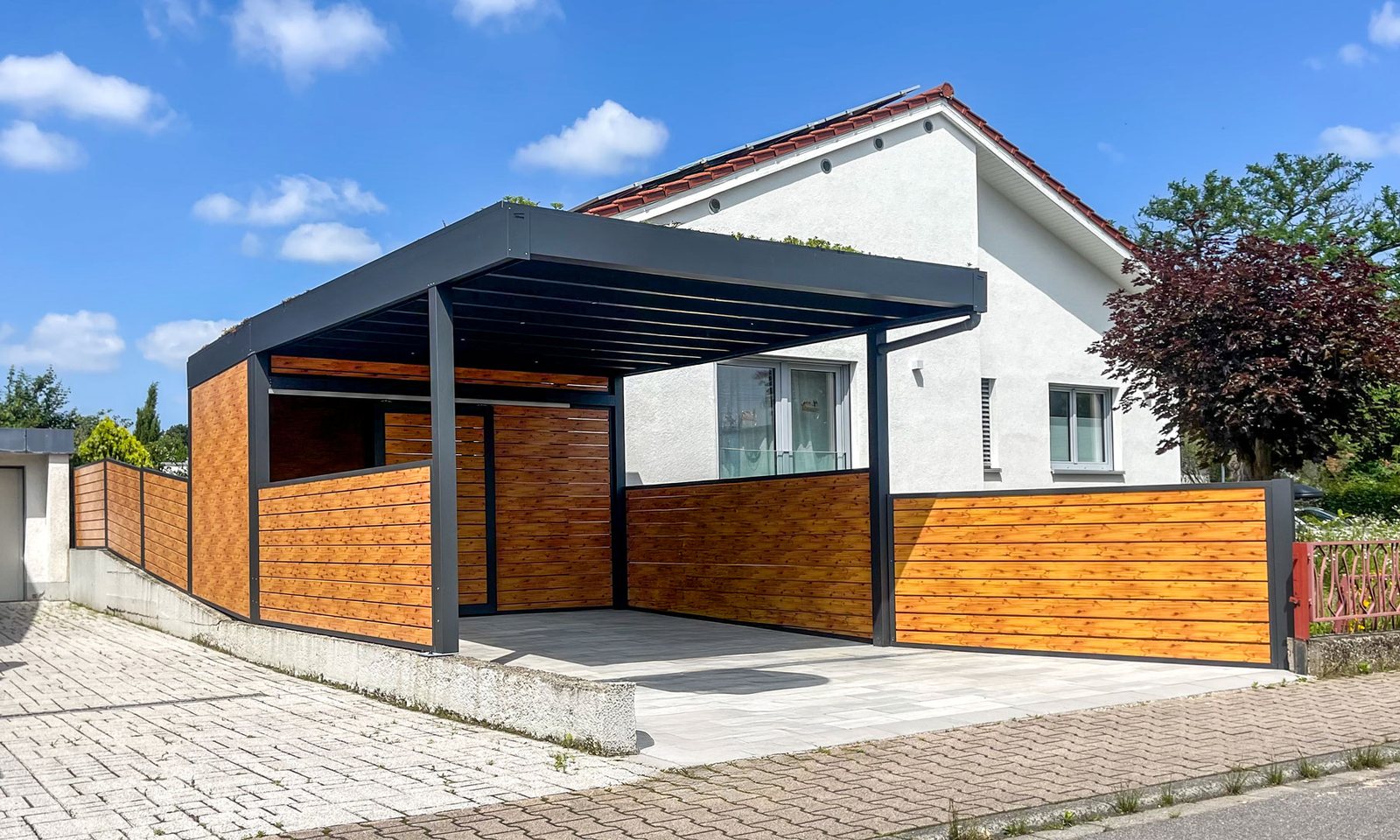 Moderner Aluminium-Carport mit Holzoptik vor einem Wohnhaus